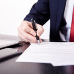 Shoot of financial director's hands signing business contract at the desk in his office