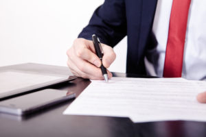 Shoot of financial director's hands signing business contract at the desk in his office
