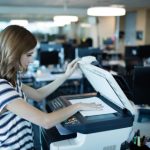 Side view of businesswoman using copy machine in office