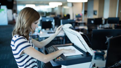 Side view of businesswoman using copy machine in office